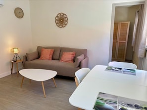 A modern living room with a sofa, a coffee table, a lamp, and a clock on the wall.