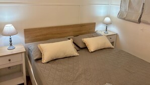 A neatly arranged bedroom with a wooden headboard, two bedside tables with lamps, a quilted bedspread, and a decorative wall piece.