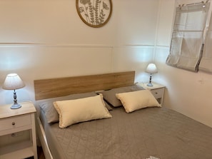 A neatly arranged bedroom with a wooden headboard, two bedside tables with lamps, a quilted bedspread, and a decorative wall piece.