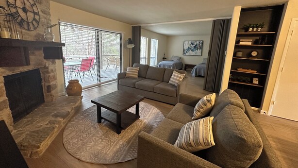 A living room with a stone fireplace, a sofa, a coffee table, and a bookshelf.