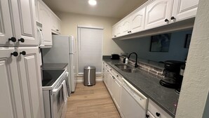 A modern kitchen with white cabinetry, a stainless steel sink, and a coffee maker.