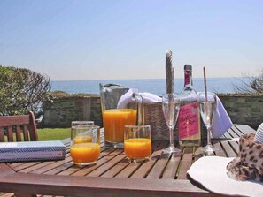 A table set with drinks and a book, overlooking a coastal view. - Watchtower (Torpoint)