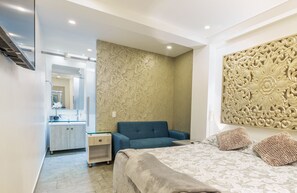 Relax in a stylish room with a large bed, sofa, and decorative wall panel.