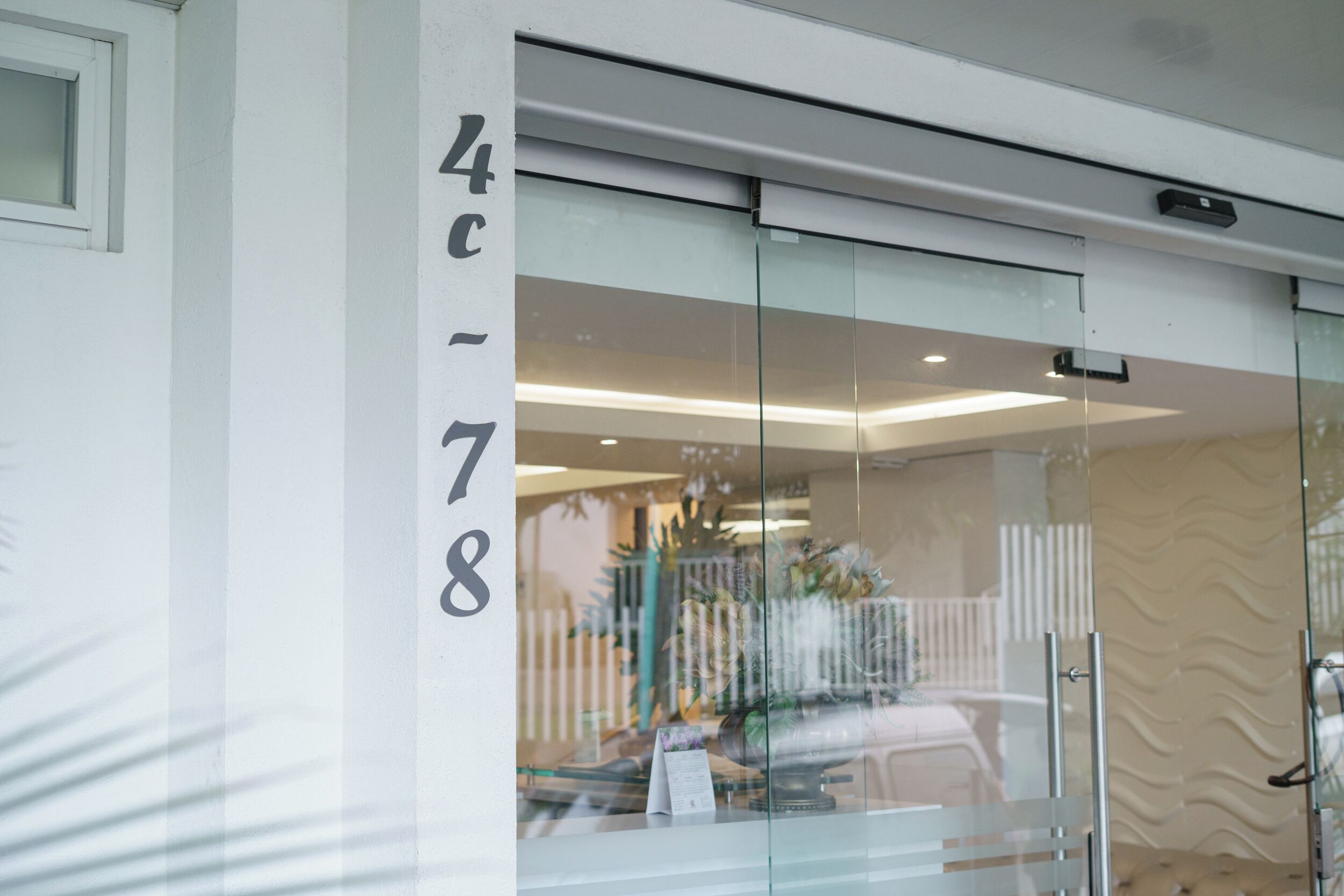 Un edificio moderno con una puerta de cristal y el número '4c-78' en la pared.