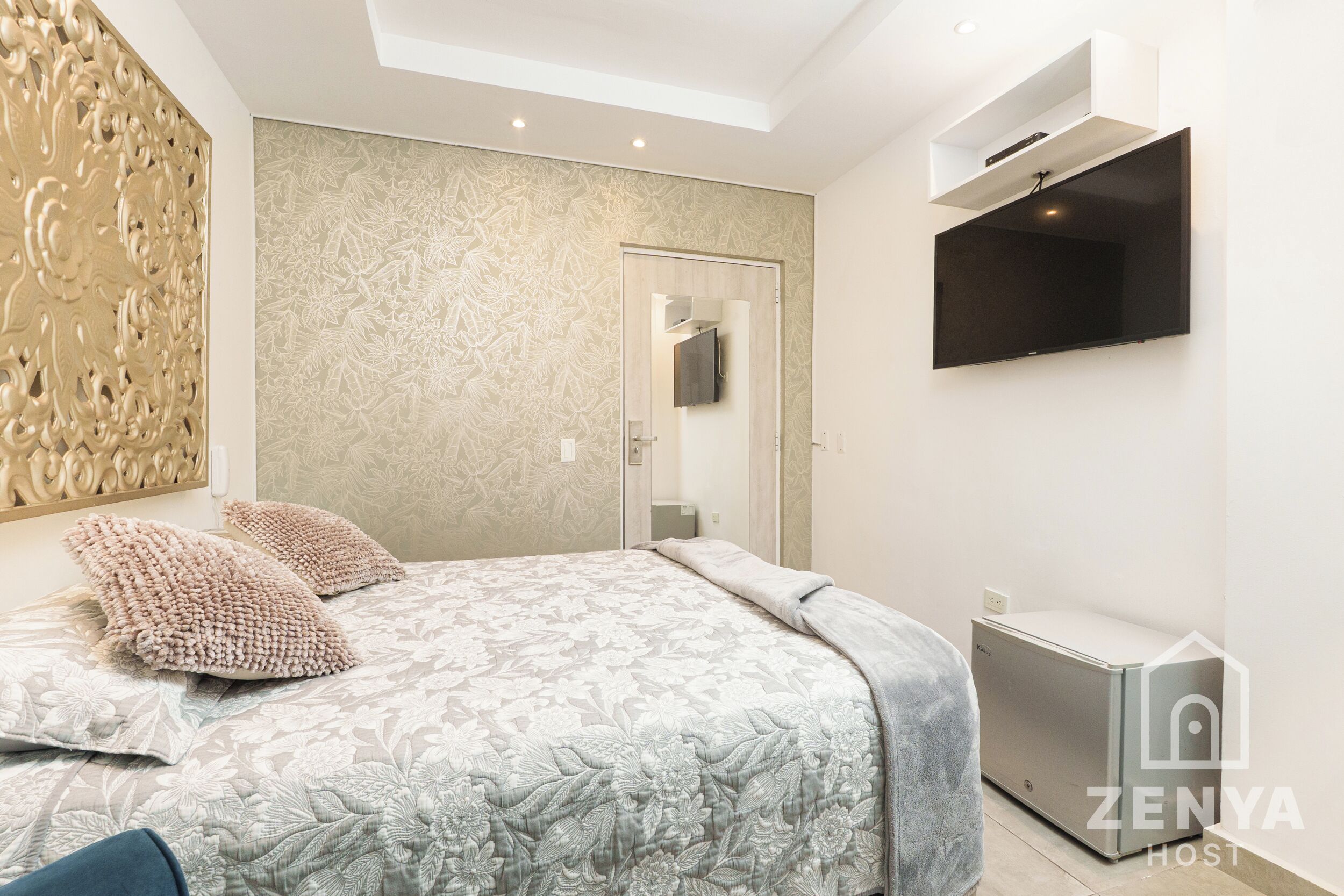 A bedroom with a bed, a TV mounted on the wall, and a built-in wardrobe.