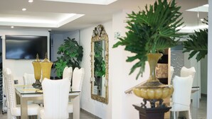 Un vestíbulo de hotel con comedor, un espejo grande y plantas en macetas.
