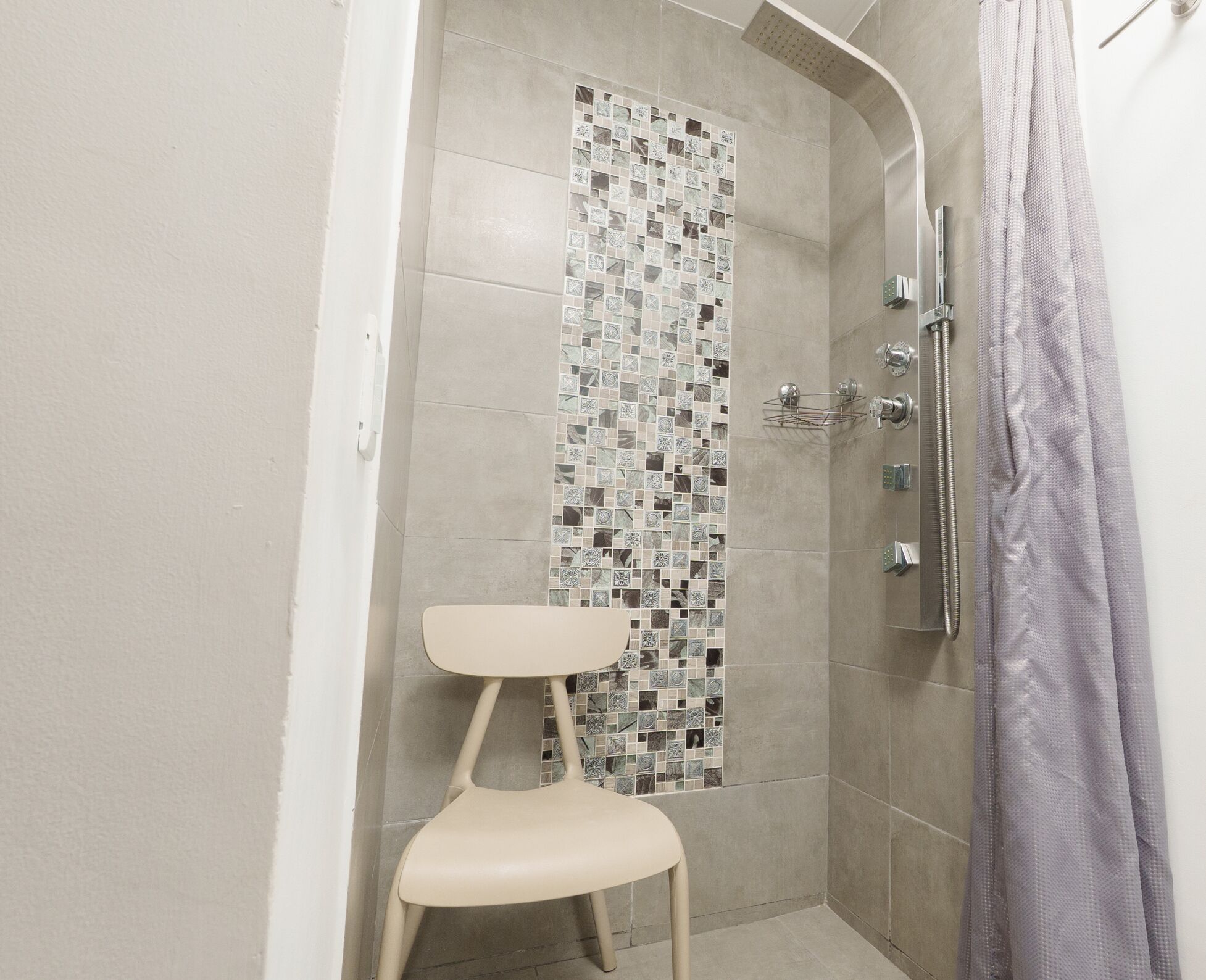 Un área de ducha con pared de azulejos, cabezal de ducha y toallero.