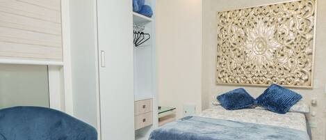 A bedroom with a bed, a wardrobe, a chair, and a decorative wall panel.