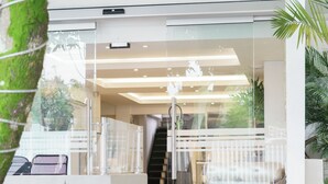 A modern hotel entrance with a glass door, a staircase leading to the interior, and potted plants on the left. - RECOVERY HOUSE BY ZENYA HOST (Cali)