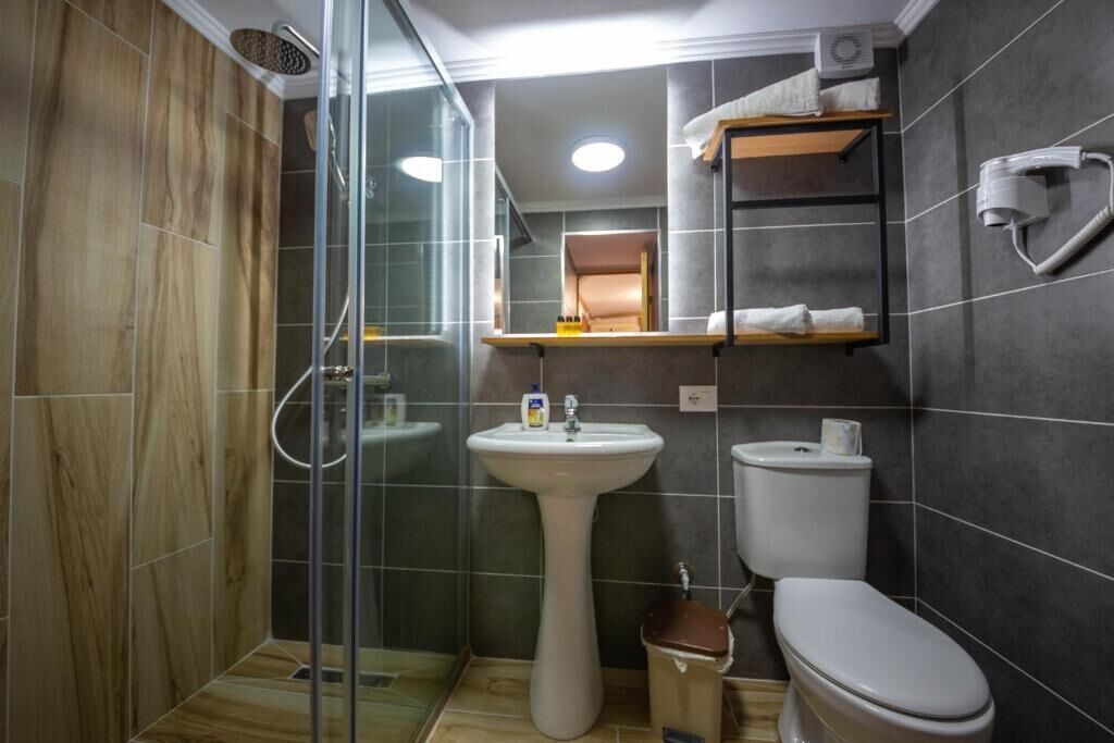 Ein Badezimmer mit Duschkabine, Standwaschbecken, Toilette und Handtuchhalter.