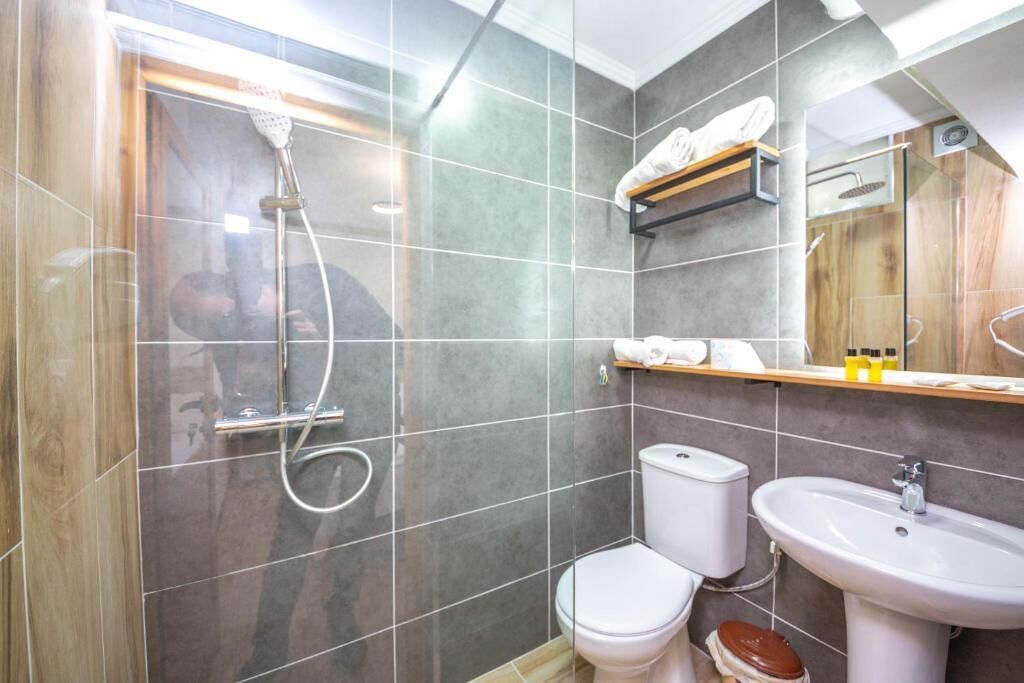 A modern bathroom with a shower, toilet, and sink.