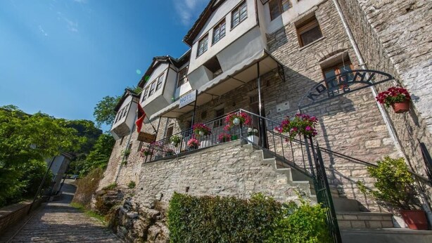A stone building with a balcony, a staircase, and flower pots. - Bed and Breakfast Kotoni (Gjirokastër)