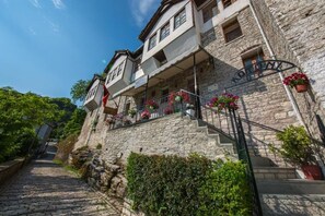 Un bâtiment en pierre doté d’un balcon, d’un escalier et de jardinières.