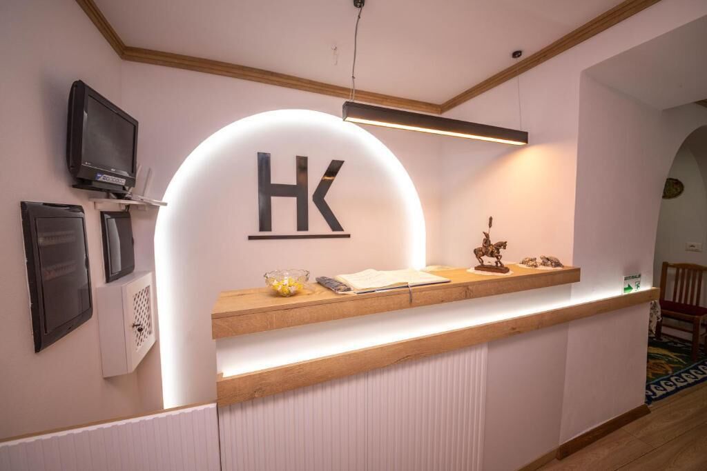 A reception desk with a sign reading "HK" and a television mounted above it.