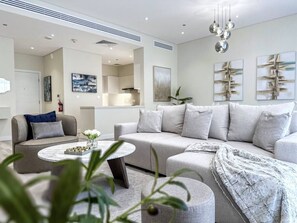 A modern living room with a sofa, a coffee table, and a decorative plant. - Fantastic Flat in Tiararesidence (Dubai)