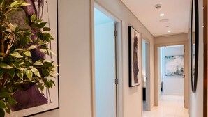 A modern hallway with a clean, white tiled floor and a glass door leading to another room. - Glamorous 3BR With Marina View (Dubai)