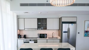 A modern kitchen with a central island, stainless steel appliances, and bar stools. - Glamorous 3BR With Marina View (Dubai)