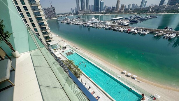 A high-rise building with a rooftop pool overlooking a marina and a beach. - Glamorous 3BR With Marina View (Dubai)
