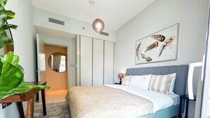 A bedroom with a bed, bedside table, and a large mirror. - Glamorous 3BR With Marina View (Dubai)