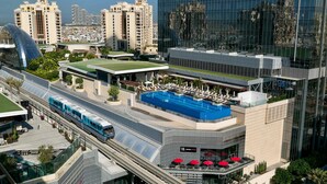 A modern hotel with a rooftop pool, a tram line, and a glass facade reflecting the cityscape. - Bird S-eye View Studio Palmtower (Dubai)