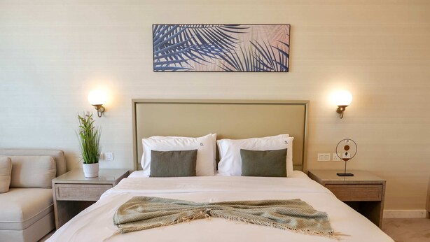 A neatly made bed with a patterned throw, a potted plant, and two bedside lamps. - Bird S-eye View Studio Palmtower (Dubai)