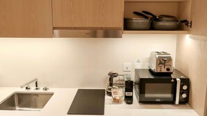 A kitchen with a stainless steel sink, a black cutting board, a toaster, a microwave, and a coffee maker. - Bird S-eye View Studio Palmtower (Dubai)