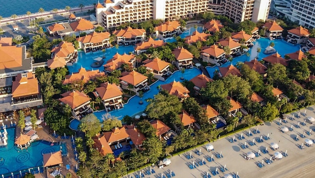 An aerial view of a resort with multiple swimming pools, beach areas, and a large hotel building. - Stunning Renovated 1BR Apartment at 5 Star Resort (Dubai)
