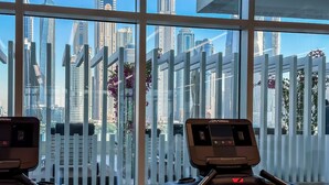 Una palestra con attrezzature sportive e vista sulla città attraverso ampie finestre.
