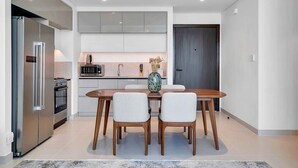 Una cucina moderna con tavolo, sedie, frigorifero, forno e microonde.
