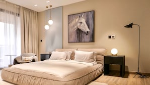 Et moderne soveværelse med en stor seng, en stol, et natbord med lampe og et billede af en hest på væggen.
