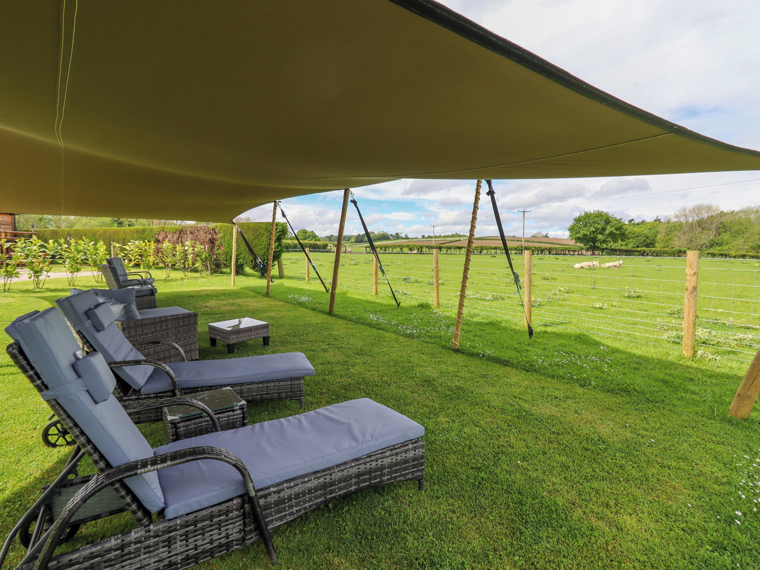 Een overdekt terras met rieten meubilair en een zonnescherm.