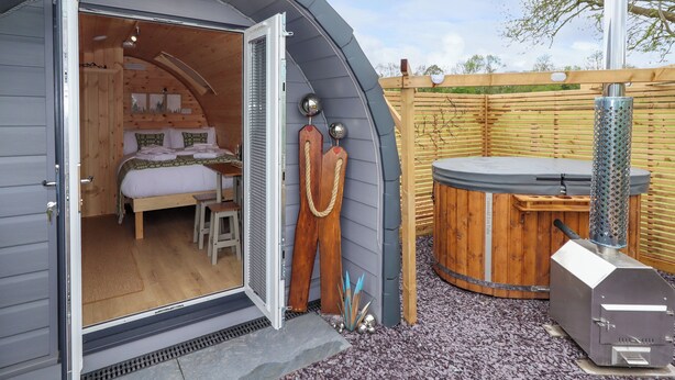 Ein gemütliches, kleines Holzhaus mit Schlafzimmer, Essbereich und Whirlpool.