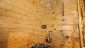 Ein Holzblockhaus-Interieur mit Holzbalkendecke, einer Uhr, einem Warnschild und einer Metallschäule, die an der Decke befestigt ist.