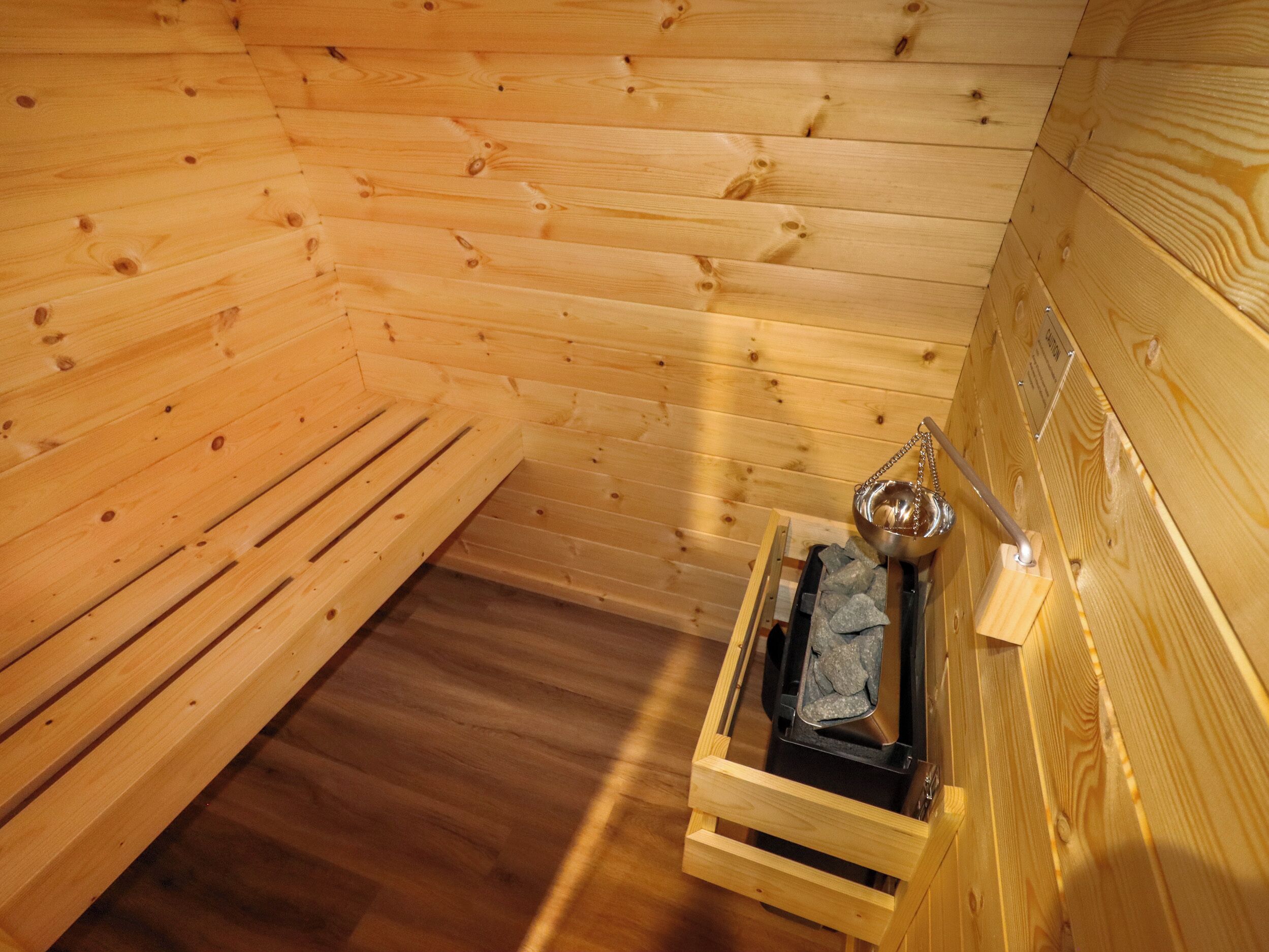 A wooden sauna with benches and a metal basin.