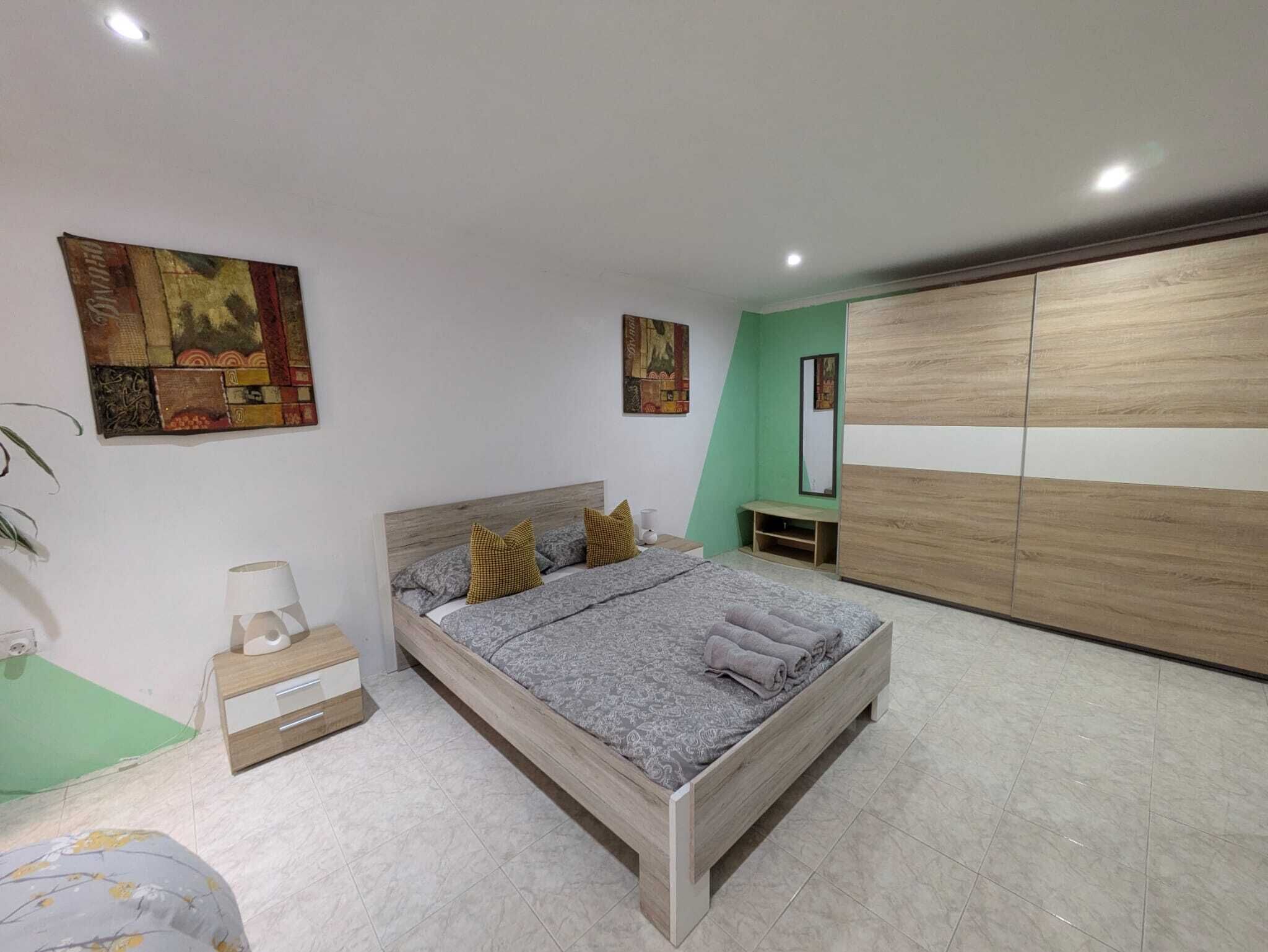 Een slaapkamer met een bed, nachtkastjes, een kledingkast en kunstwerken aan de muur.