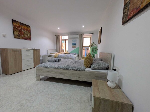 Une chambre à coucher avec un lit, des tables de chevet, une armoire et une fenêtre avec des rideaux.