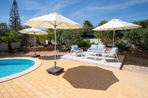 Ein Poolbereich mit Whirlpool, Liegestühlen und Sonnenschirmen.