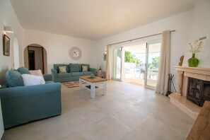 A spacious living room with a sofa set, a coffee table, and a fireplace. - Pomba Beautifully Renovated With Heated Pool (Lagoa)
