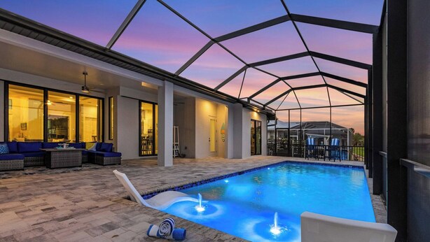 Una piscina interna con tetto in vetro, area relax con divani e patio coperto.