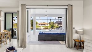 Un soggiorno moderno con un'ampia vetrata che dà su una zona piscina.