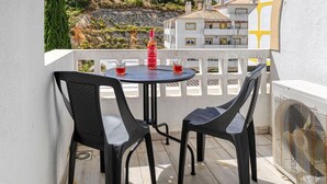 A balcony with two chairs and a table, overlooking a hillside with buildings. - Azula Bright and Airy 2 Bedroom Apartment With p (Lagoa)