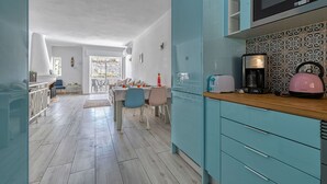 A modern kitchen with teal cabinetry, a microwave, a toaster, and a coffee maker. - Azula Bright and Airy 2 Bedroom Apartment With p (Lagoa)