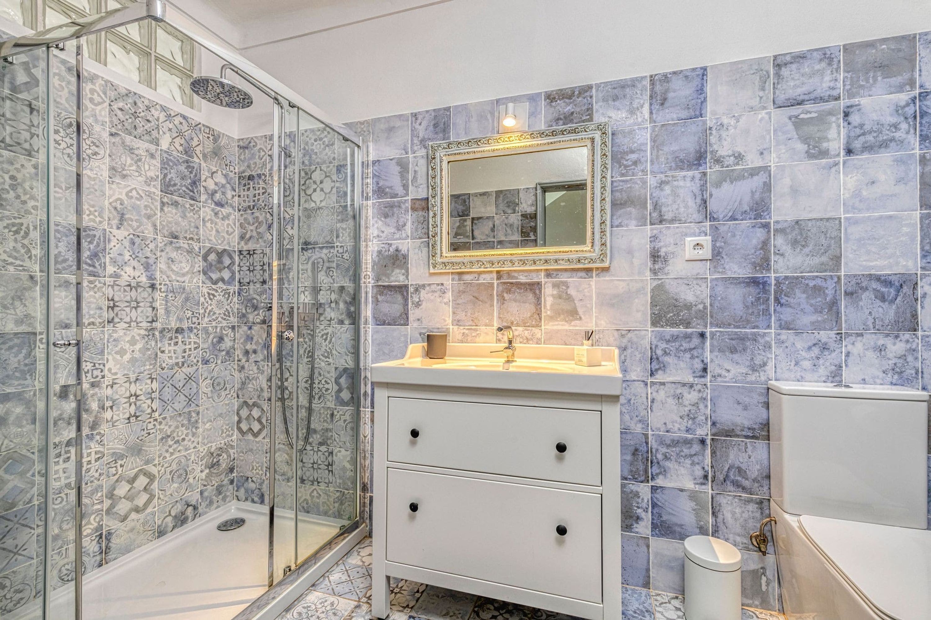 A bathroom with a shower, a sink with a mirror, and a toilet.