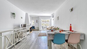 A bright, open-plan living area with a dining table set for two, a sofa, and a TV. - Azula Bright and Airy 2 Bedroom Apartment With p (Lagoa)