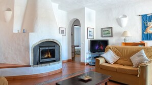 Un salon avec une cheminée, un canapé, un téléviseur et une table basse.