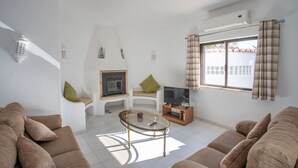 A living room with a fireplace, sofa, TV, and a window with curtains. - Carosim Quiet Location Close to Beach Private (Lagoa)