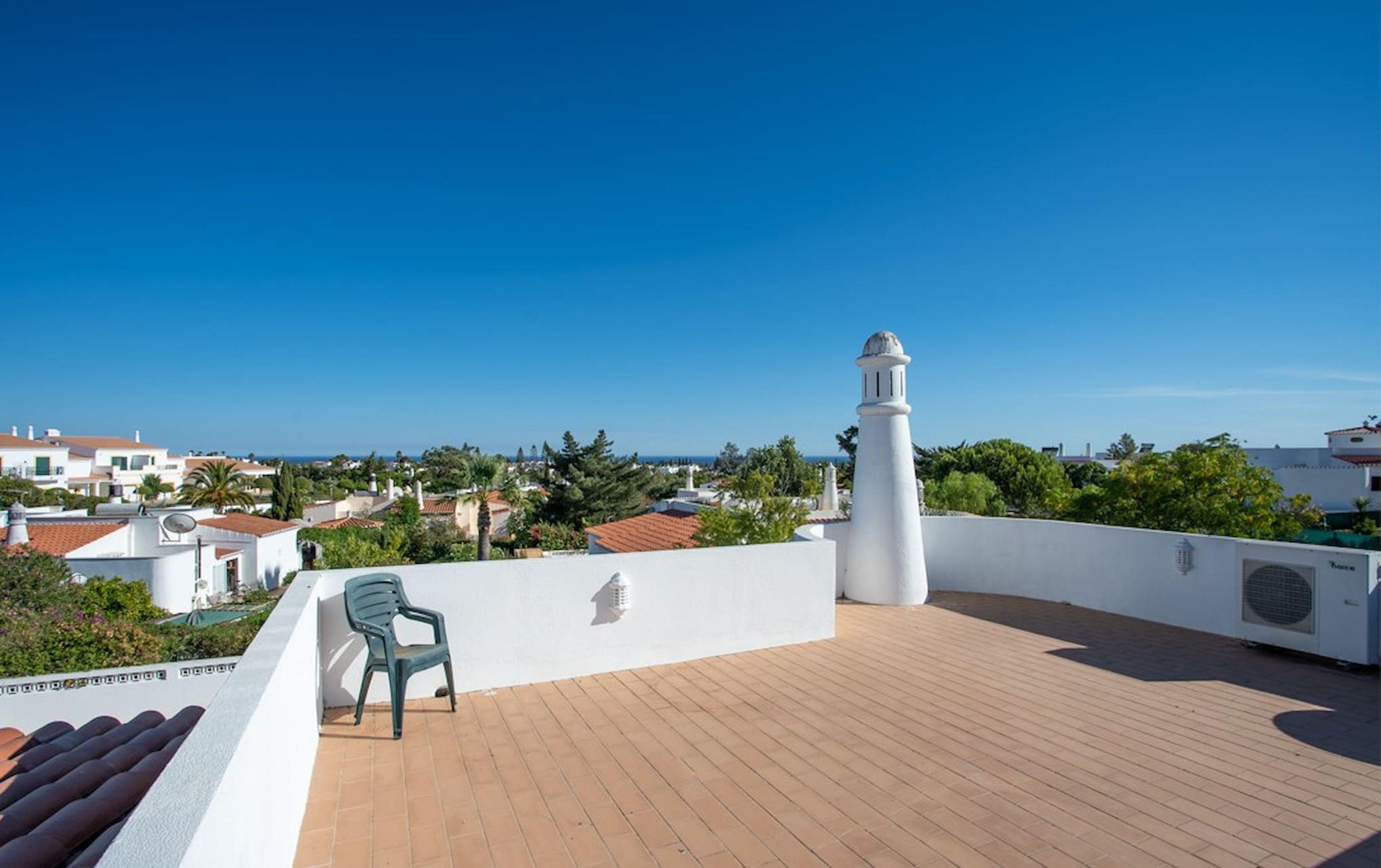 Eine Dachterrasse mit Blick auf das Meer, ein weißer Turm und ein Stuhl.