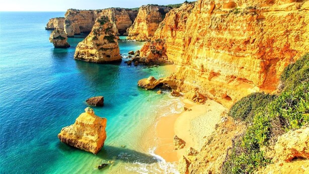 A coastal landscape with cliffs and clear blue waters.