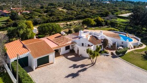 A coastal property with a swimming pool, white buildings, and a view of the sea.