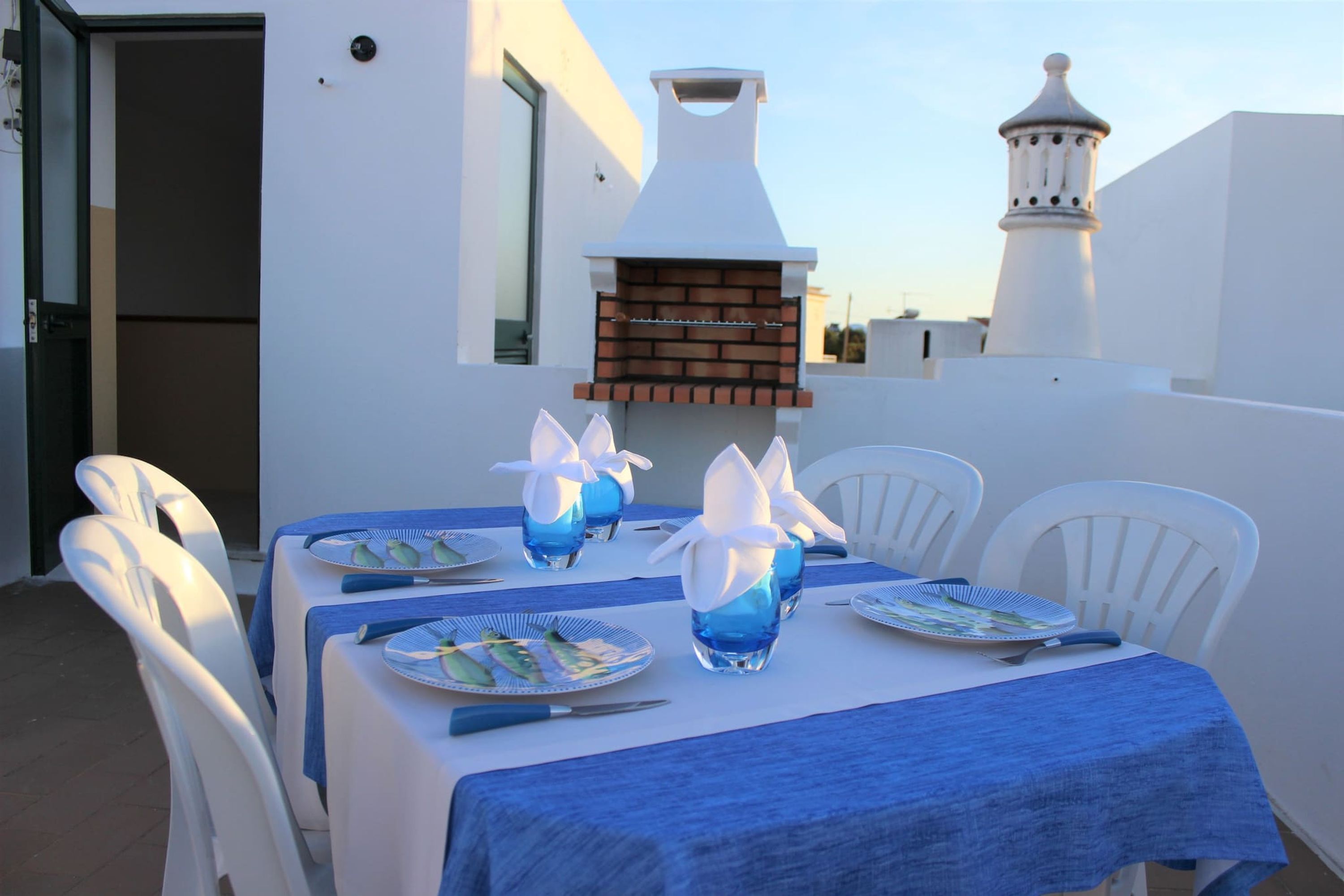 A table set for four with blue tablecloths, white chairs, and plates with blue and white designs.